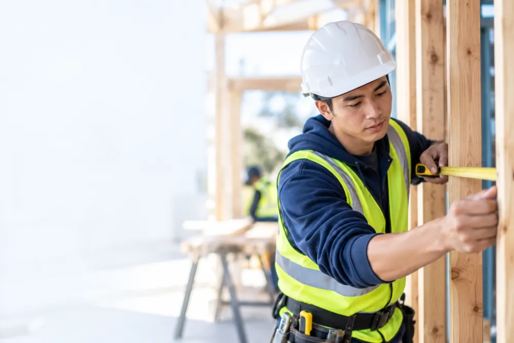 Trainee measuring timber framing on a building site